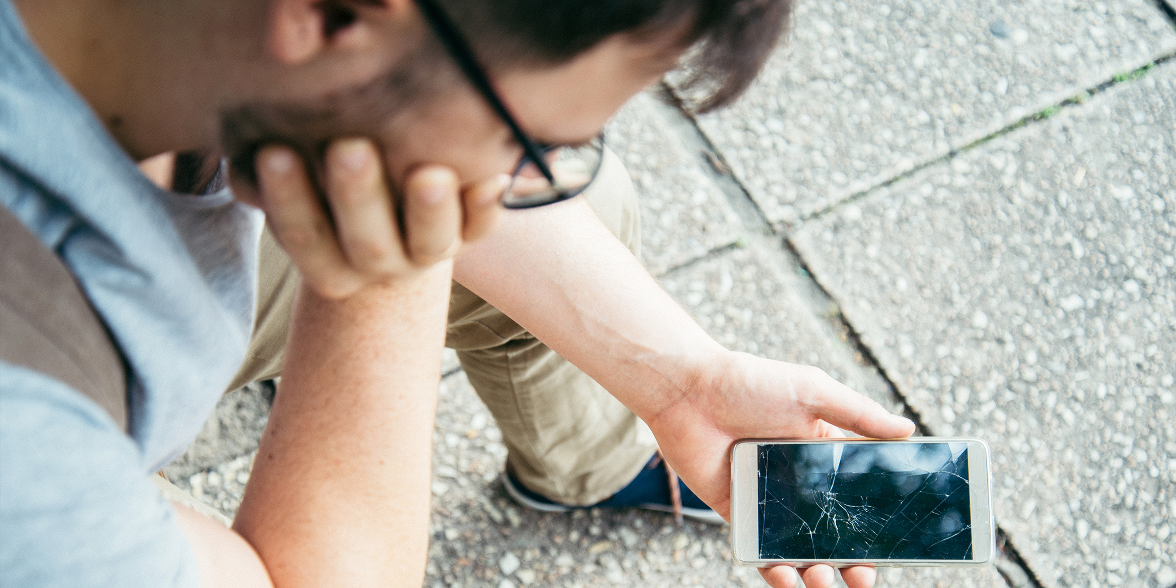 Un hombre mirando un teléfono roto | Fuente: Shutterstock