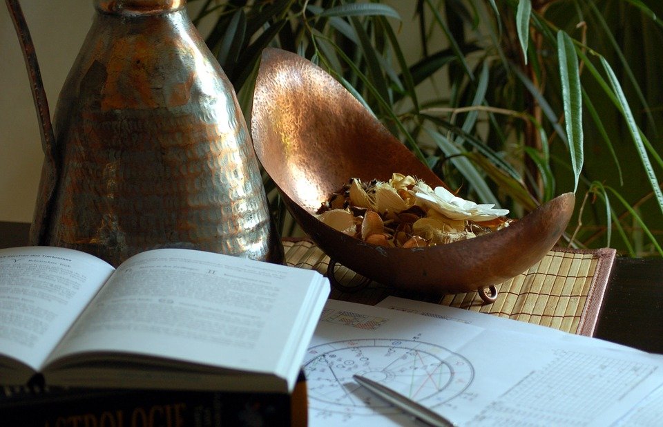 Carta astral junto a unos libros sobre una mesa. | Foto: Pixabay