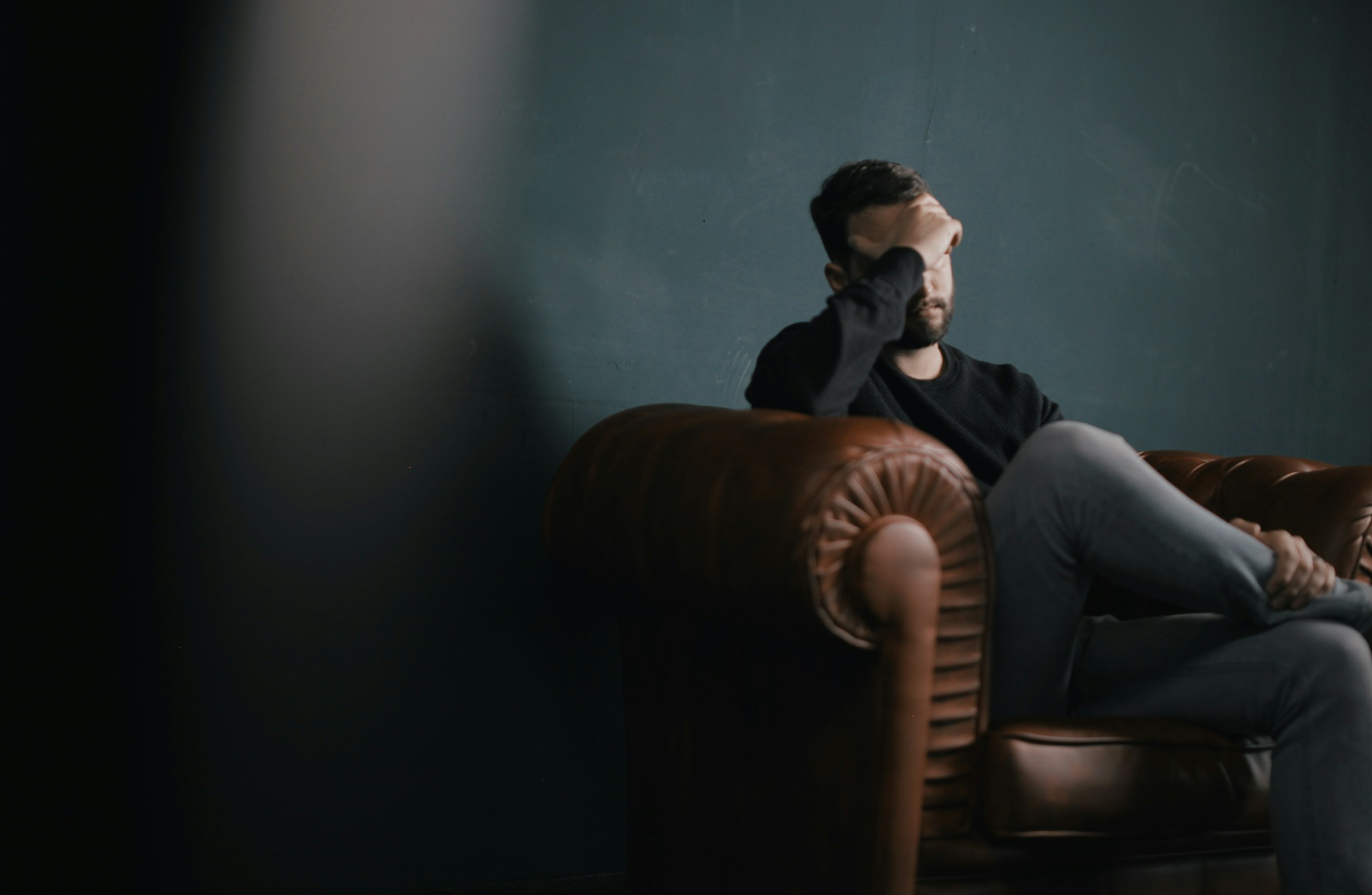 Un hombre sentado en un sofá y sujetándose la cabeza | Foto: Unsplash