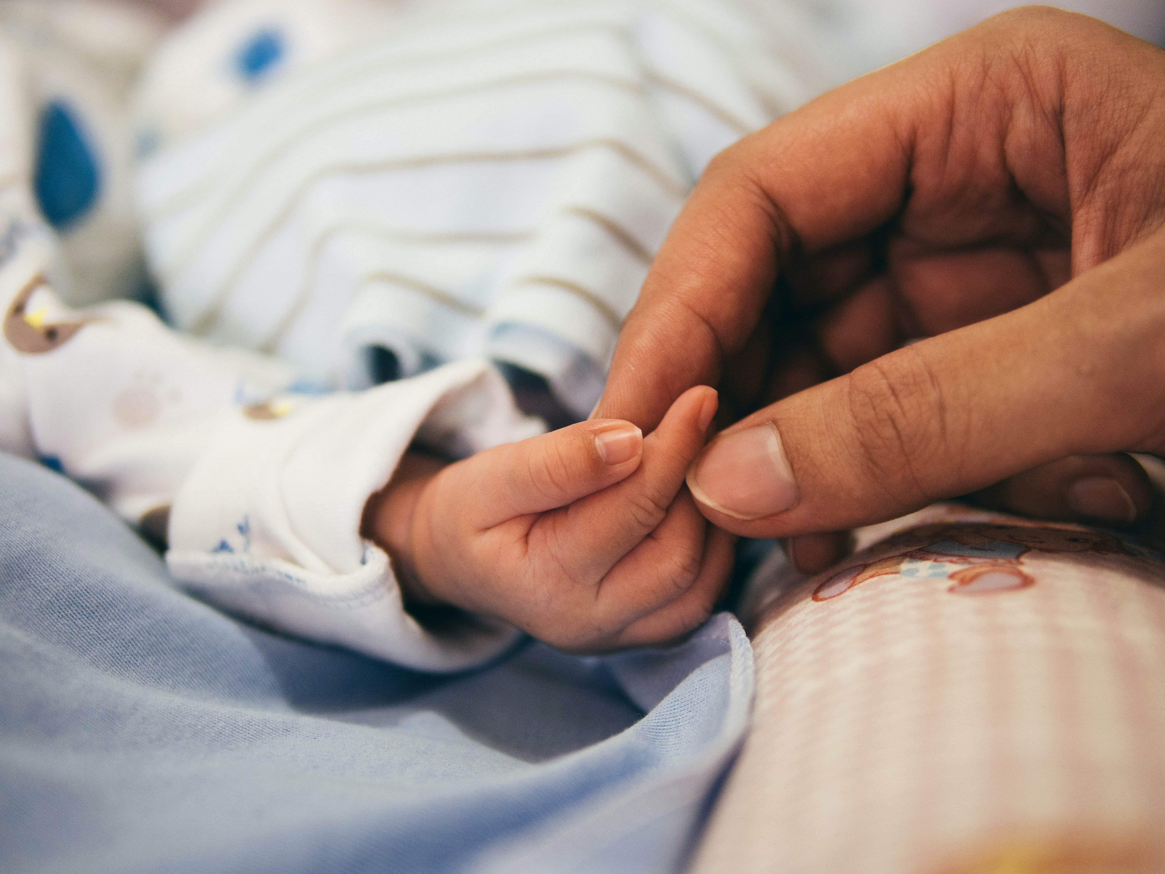 Una persona sosteniendo la mano de un bebé. | Foto: Unsplash