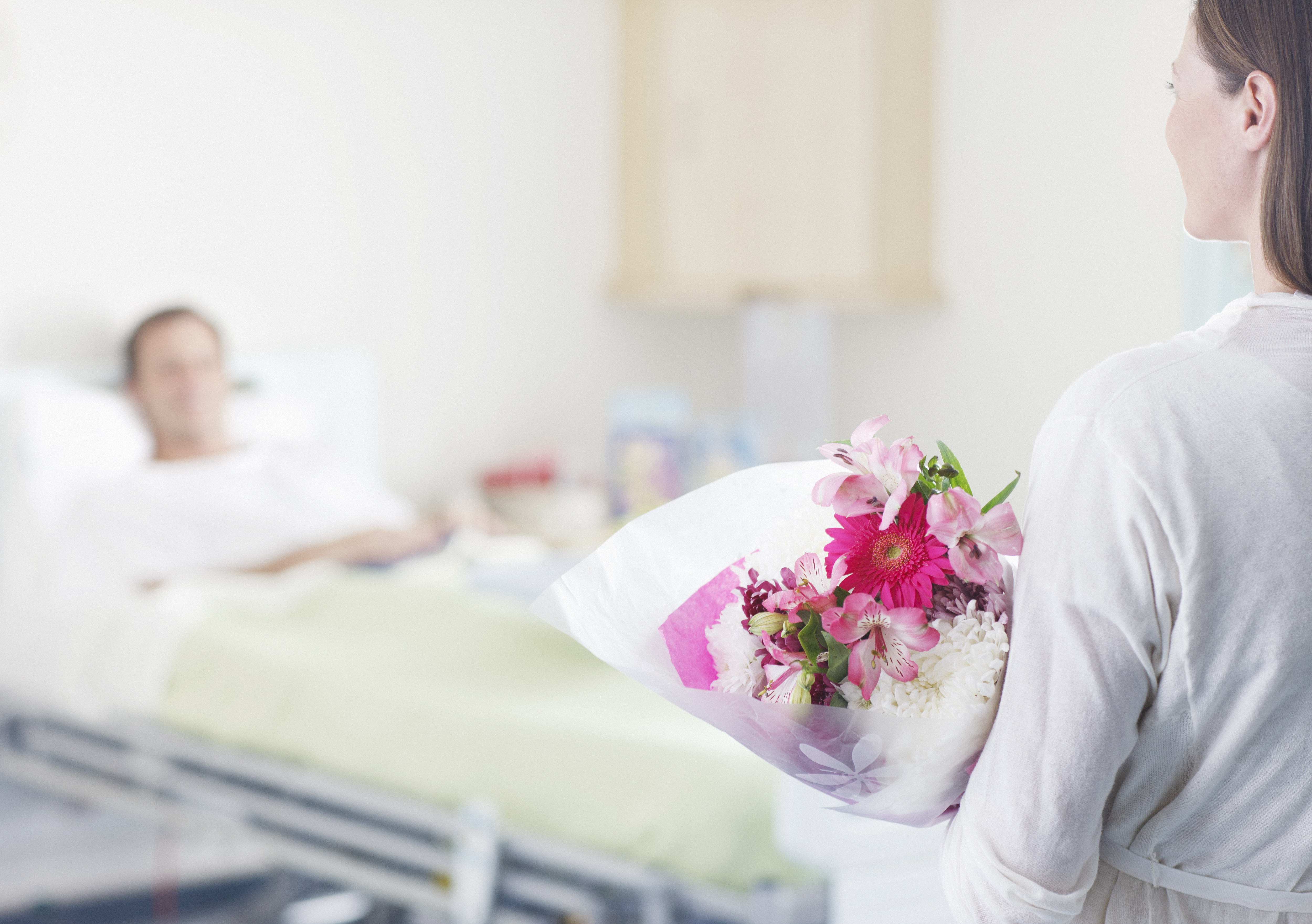 Una mujer lleva flores a un hombre en un hospital | Foto: Getty Images