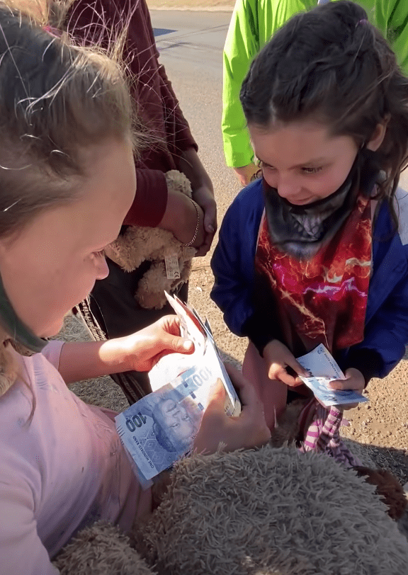 Una niña cuenta el dinero que le ha dado un amable desconocido. | Foto: Youtube.com/BI Phakathi