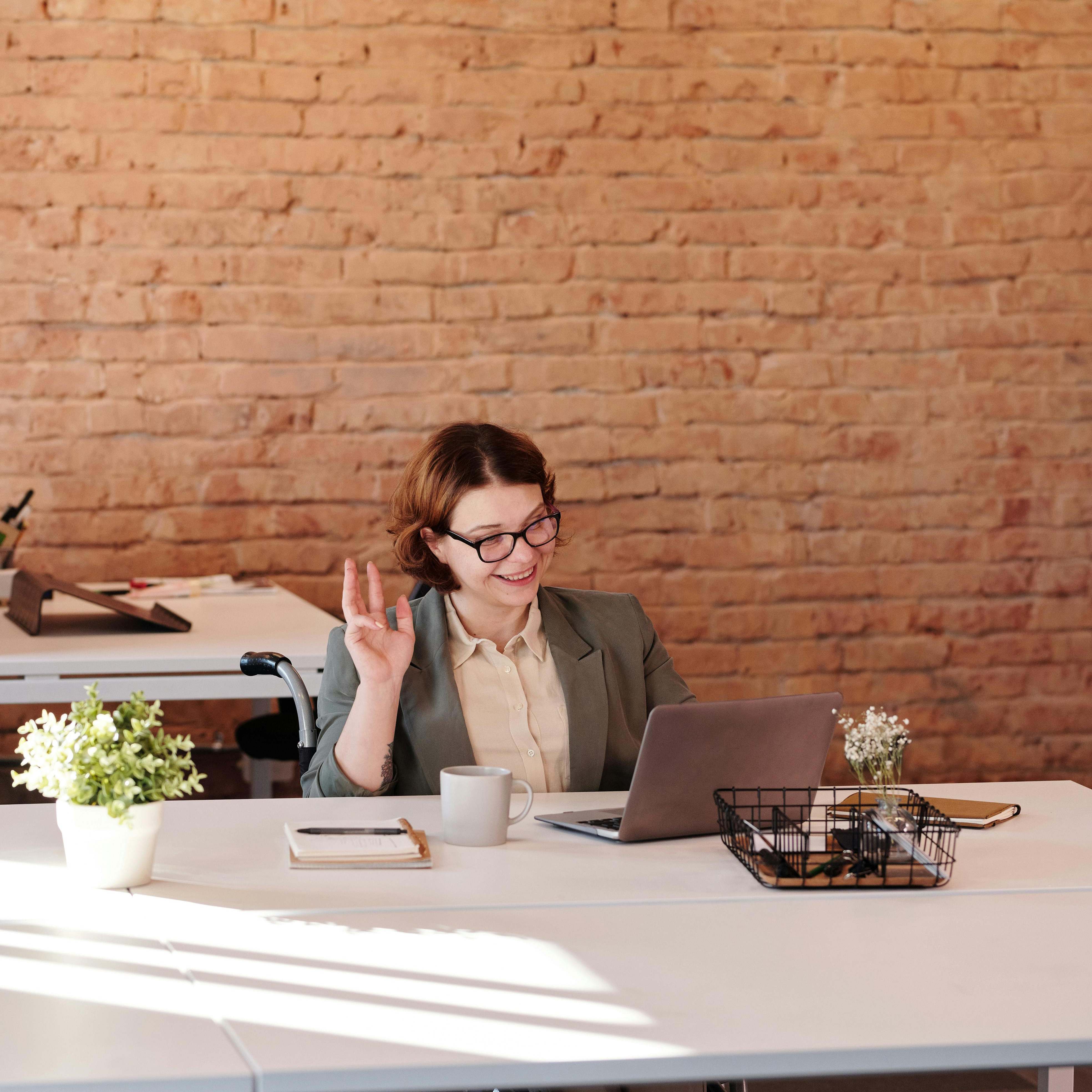 Una mujer en una mesa de trabajo, sonriendo | Fuente: Pexels