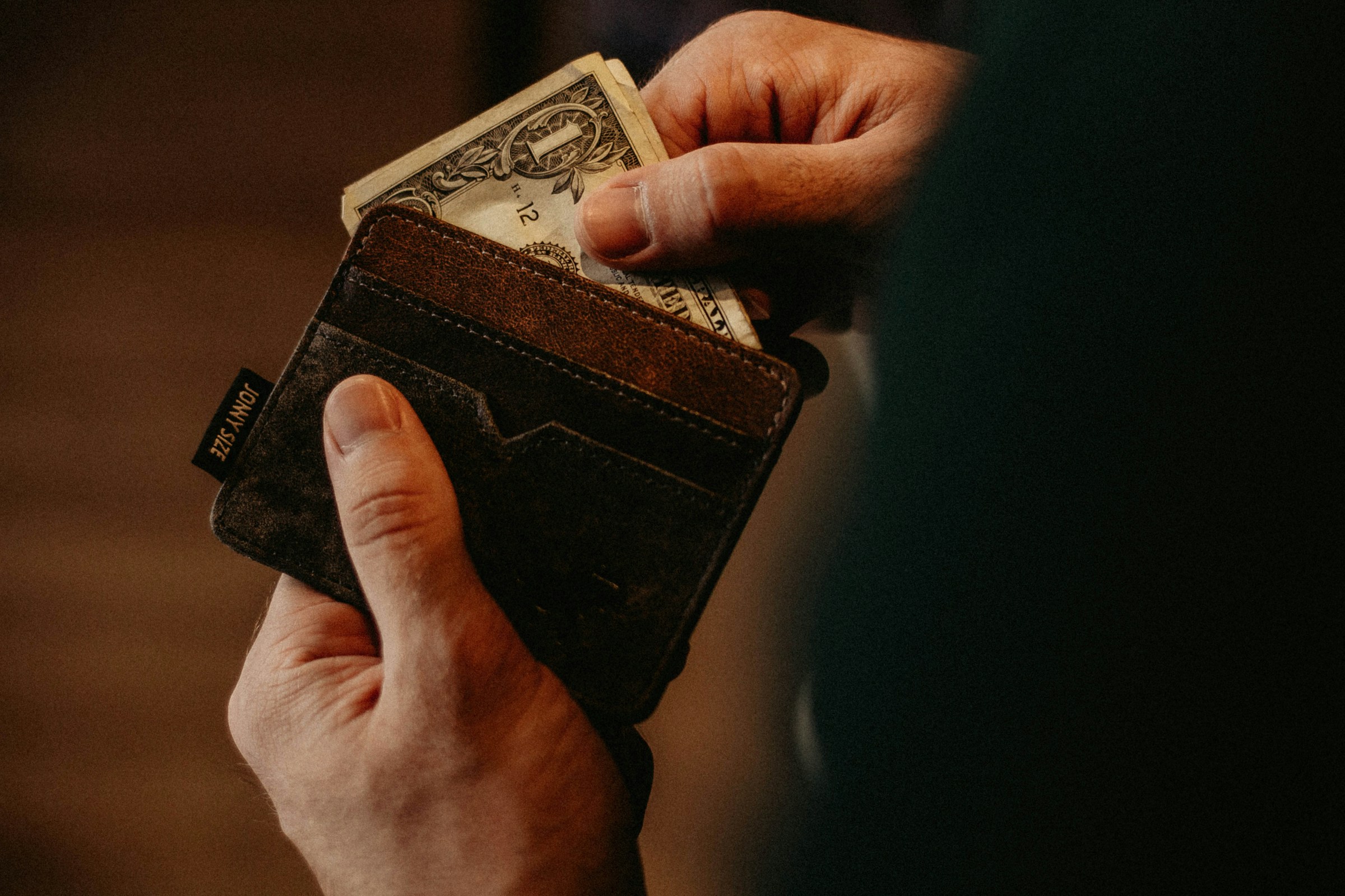 Un hombre abriendo su cartera | Fuente: Unsplash