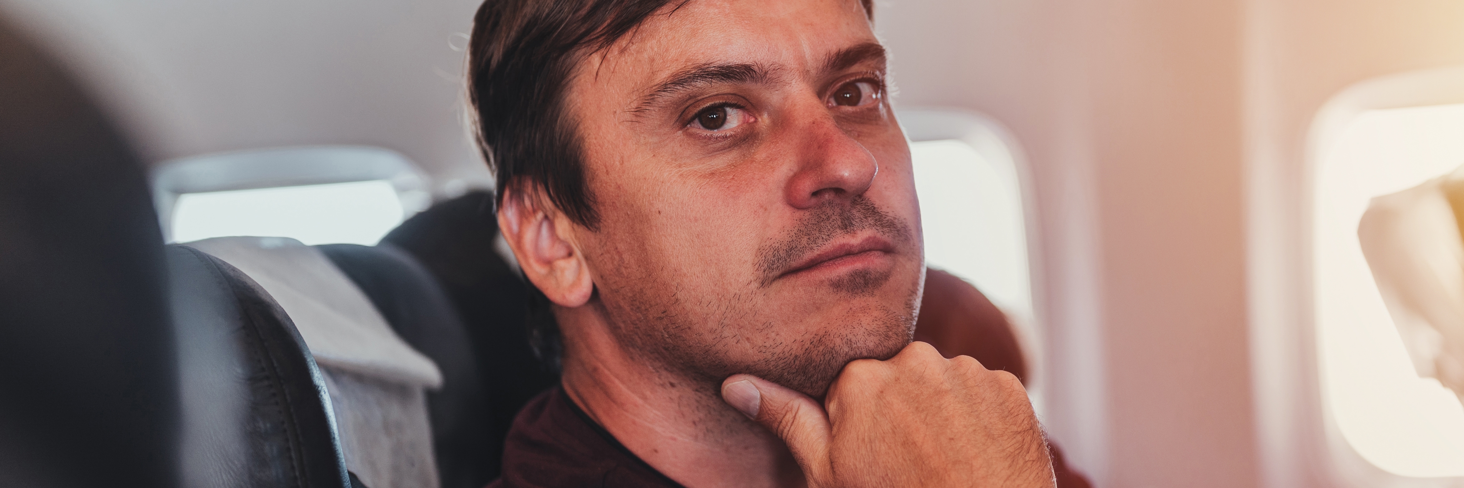 Hombre pensativo y culpable dentro de un avión | Fuente: Shutterstock