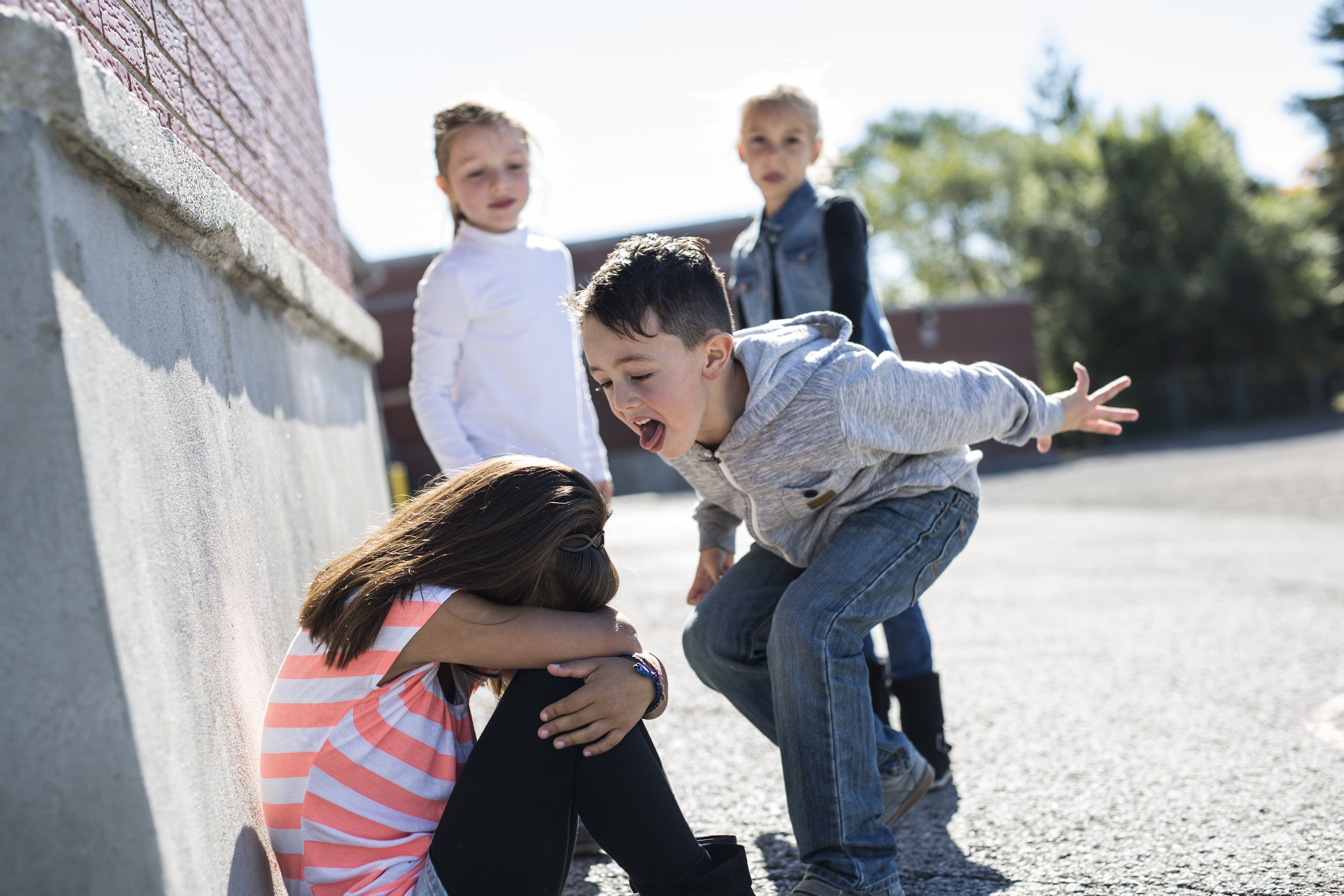 Niña triste siendo víctima de bullying escolar en medio del recreo. Fuente: Shutterstock