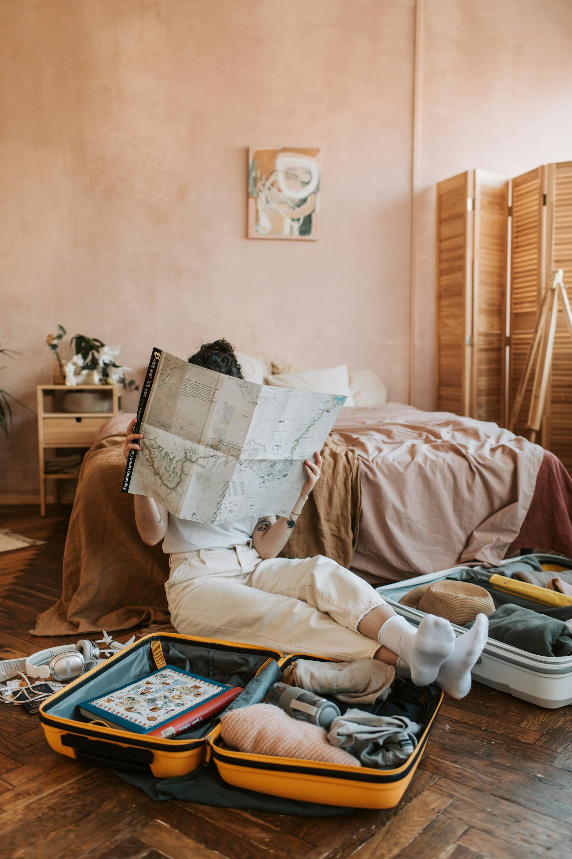 Una mujer mirando un mapa con equipaje a su alrededor | Fuente: Pexels
