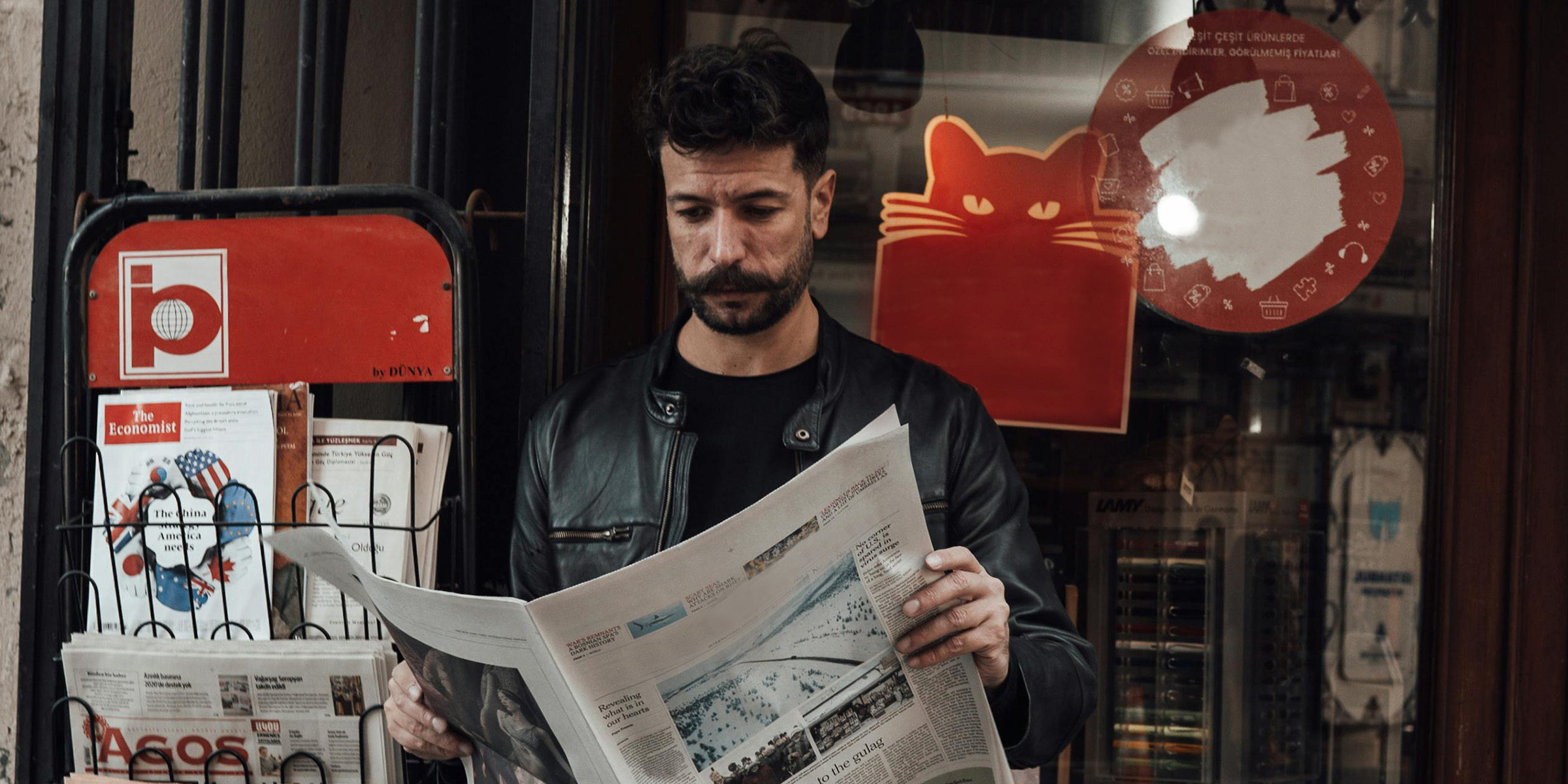 Hombre leyendo un periódico junto a la librería | Fuente: Pexels