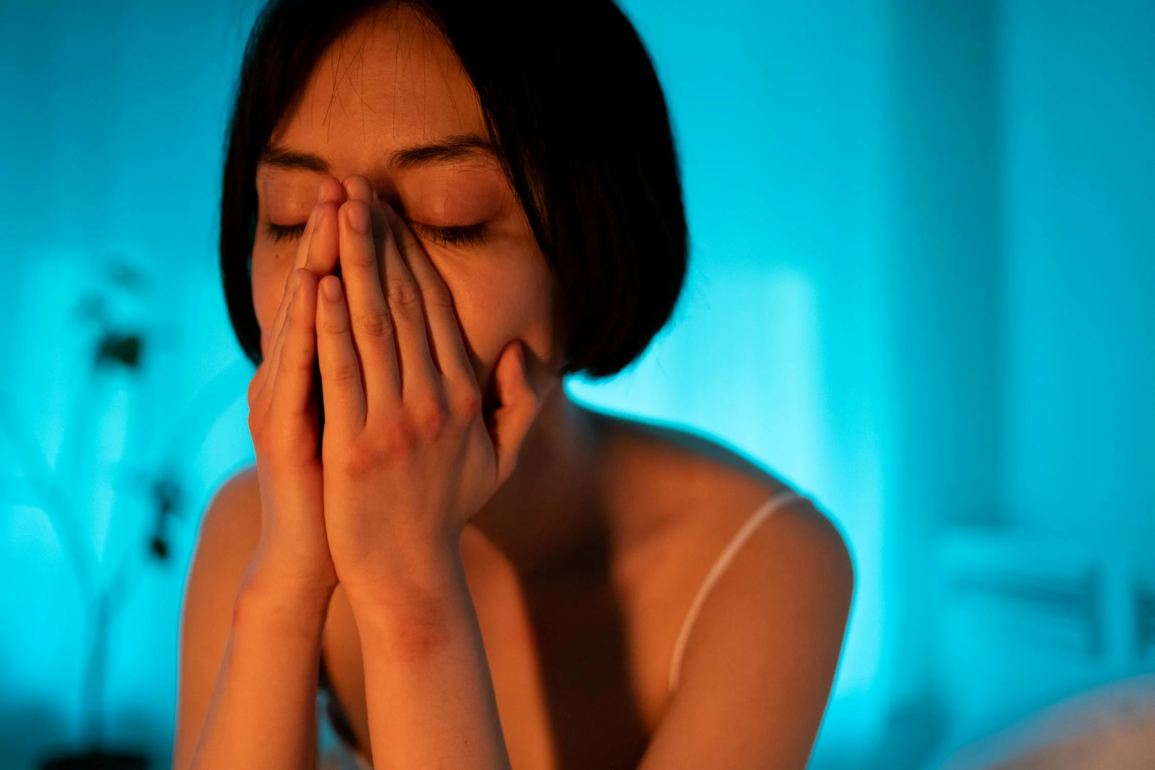 Una mujer triste en una habitación con luz azul | Fuente: Pexels