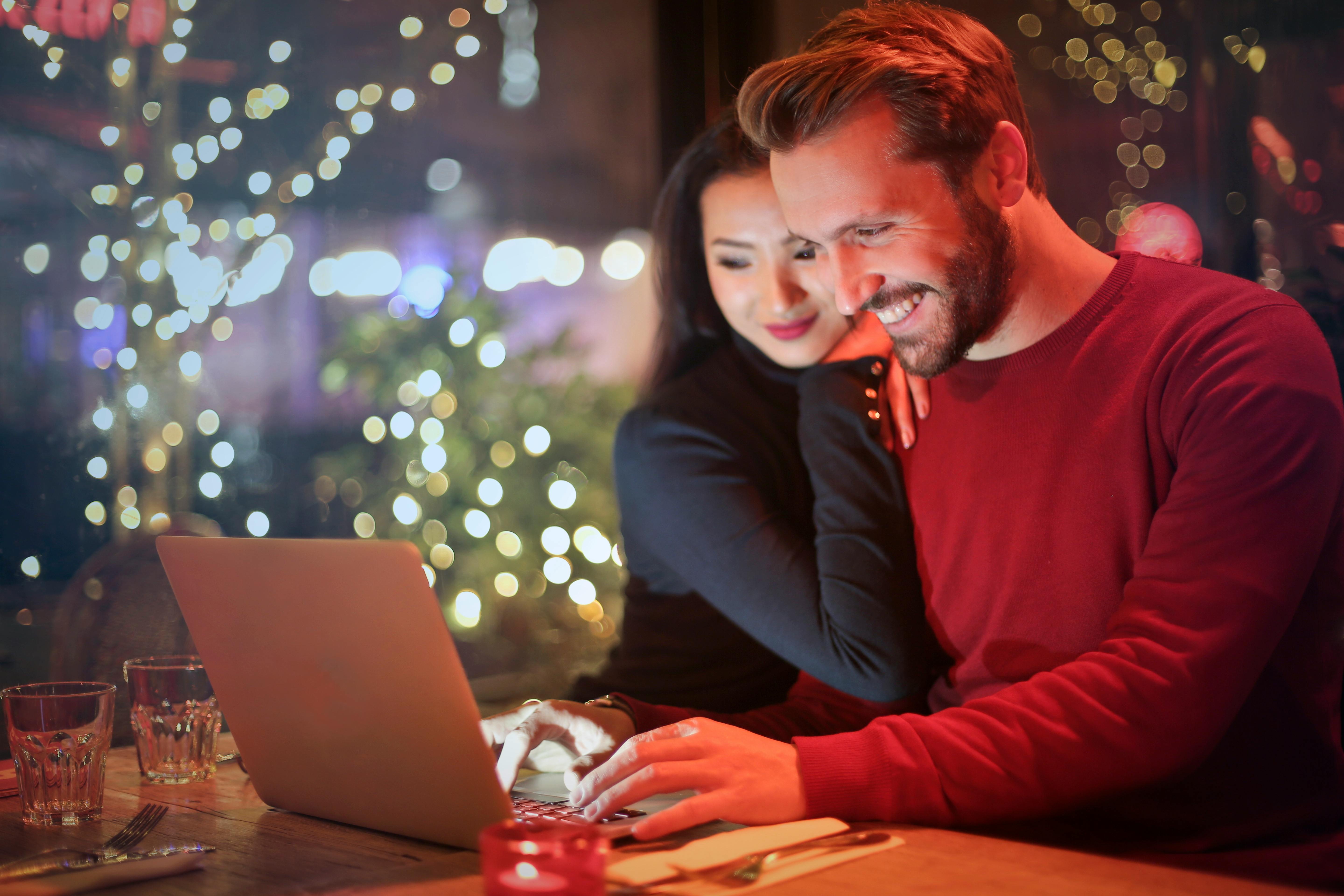 Una pareja feliz estrechando lazos mientras mira un portátil | Fuente: Pexels