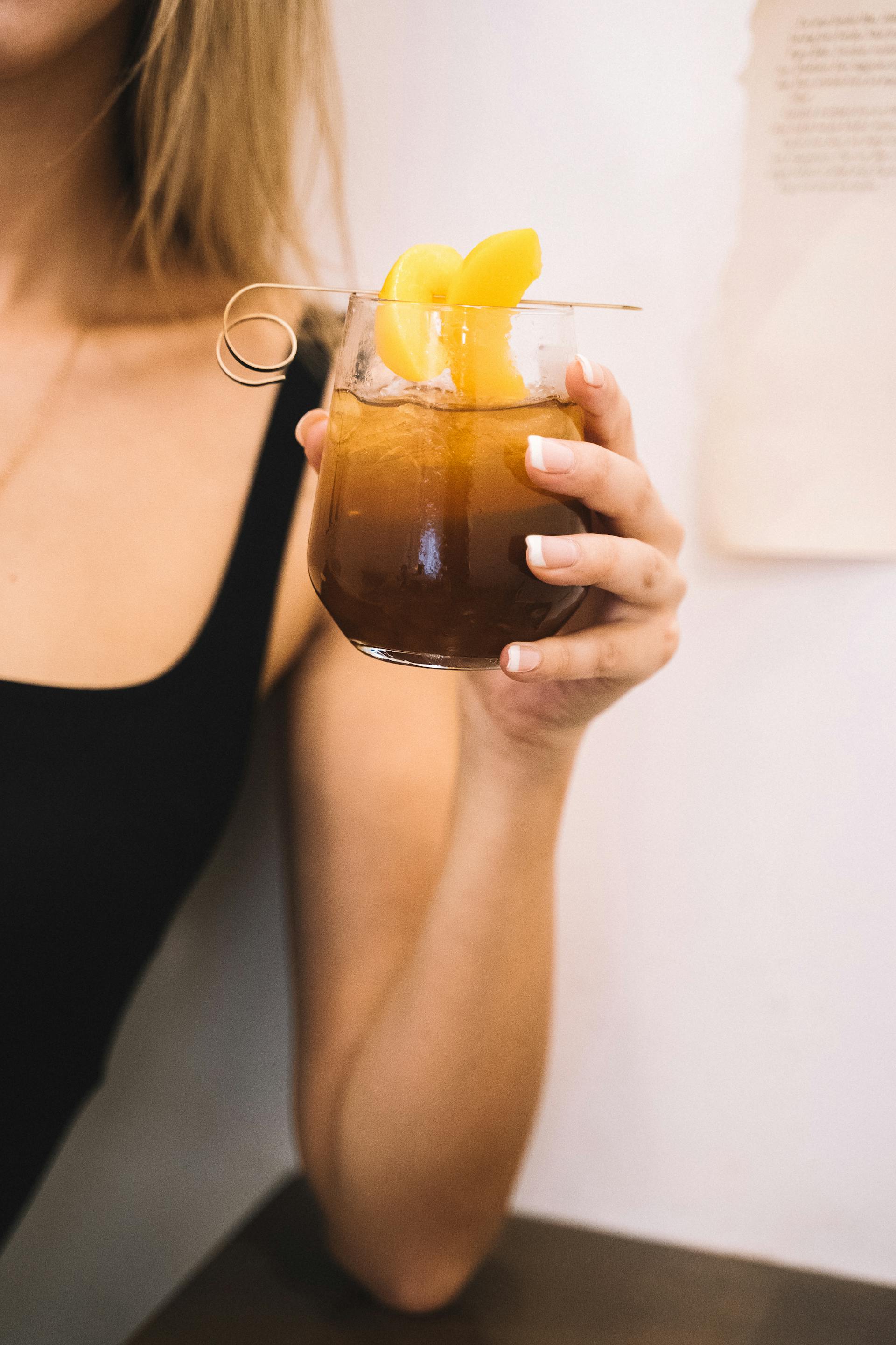 Una mujer con una taza de té helado en la mano | Fuente: Pexels