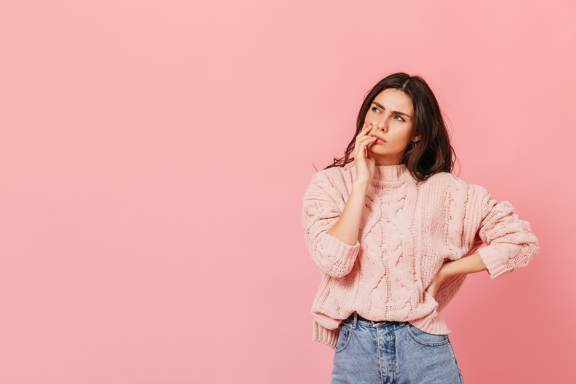 Una mujer con un jersey rosa, pensando | Fuente: Freepik