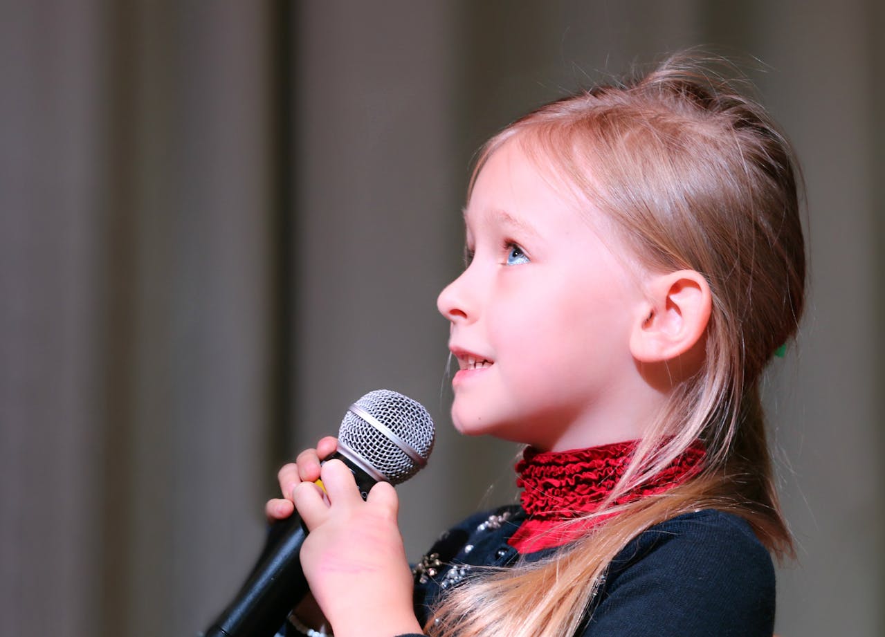 Una niña encantada sujetando un micro | Fuente: Pexels
