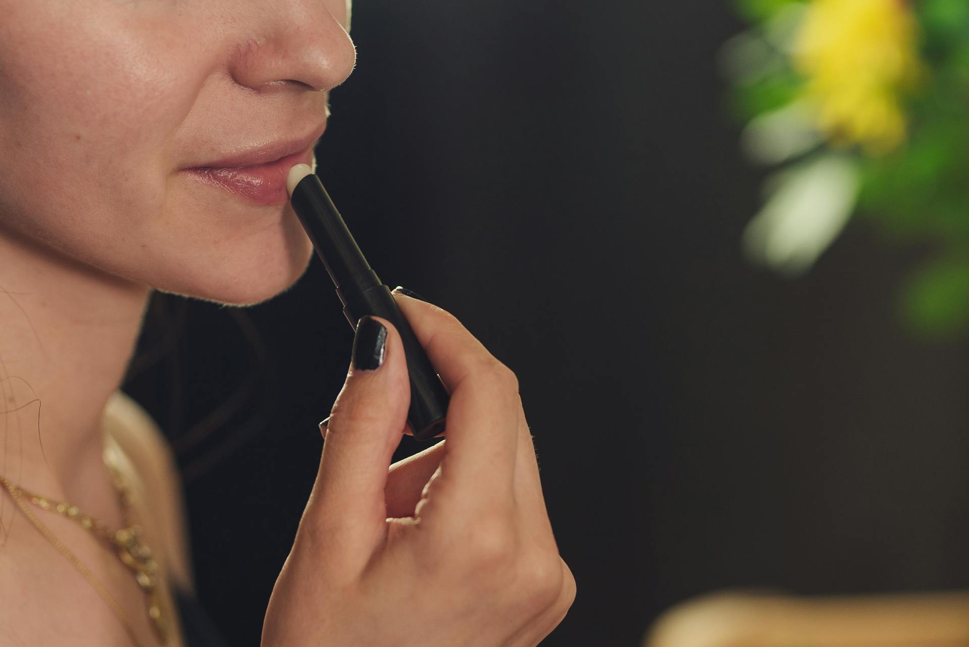 Primer plano de una mujer pintándose los labios | Fuente: Pexels