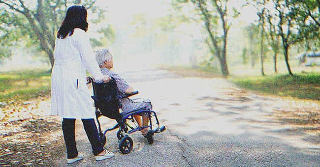 Una enfermera empujando la silla de ruedas de una anciana en un camino rodeado de naturaleza. | Foto: Shutterstock