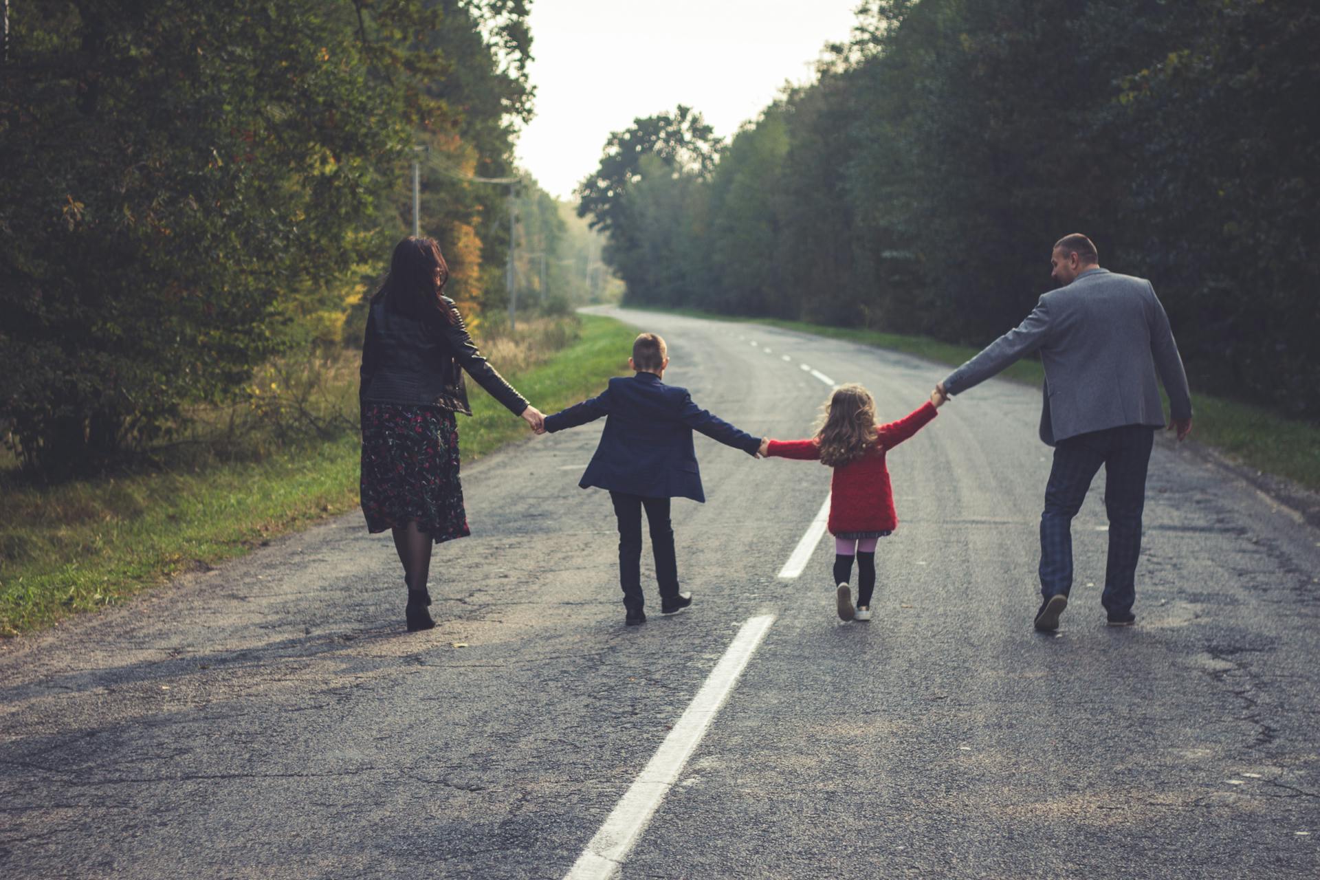 Una familia de cuatro personas caminando por una carretera | Fuente: Pexels