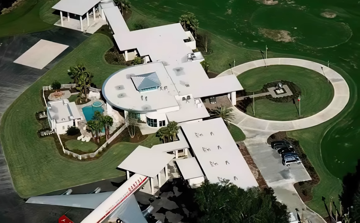 La propiedad de Travolta, pensada para la aviación, combina una vivienda moderna de líneas curvas, jardines, una piscina y espacio para una aeronave de gran tamaño. | Fuente: YouTube/@Therichest