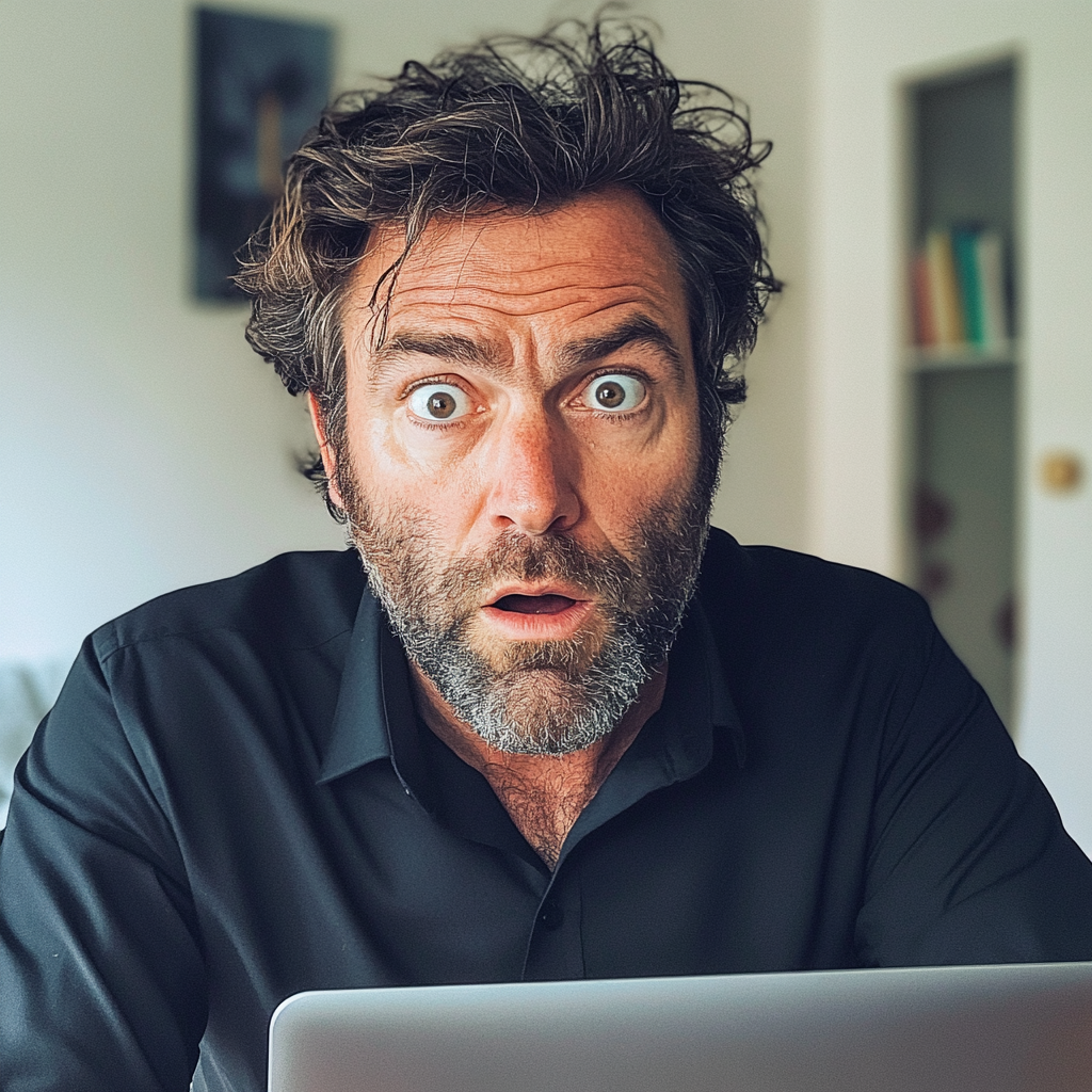 Un hombre con los ojos muy abiertos sentado con su ordenador | Fuente: Midjourney