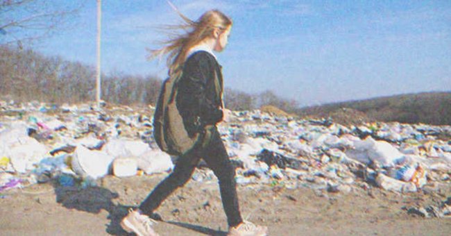 Una niña caminando frente a un basurero. | Foto: Shutterstock